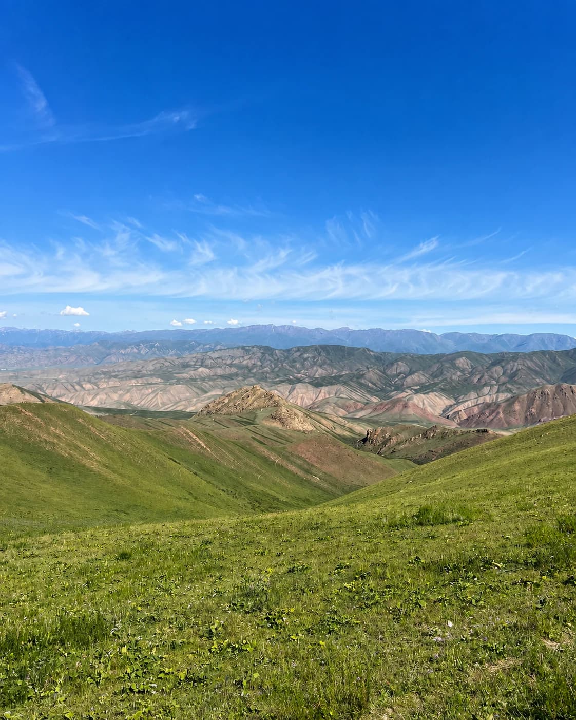 Layered mountain ridges across a green Kyrgyz valley