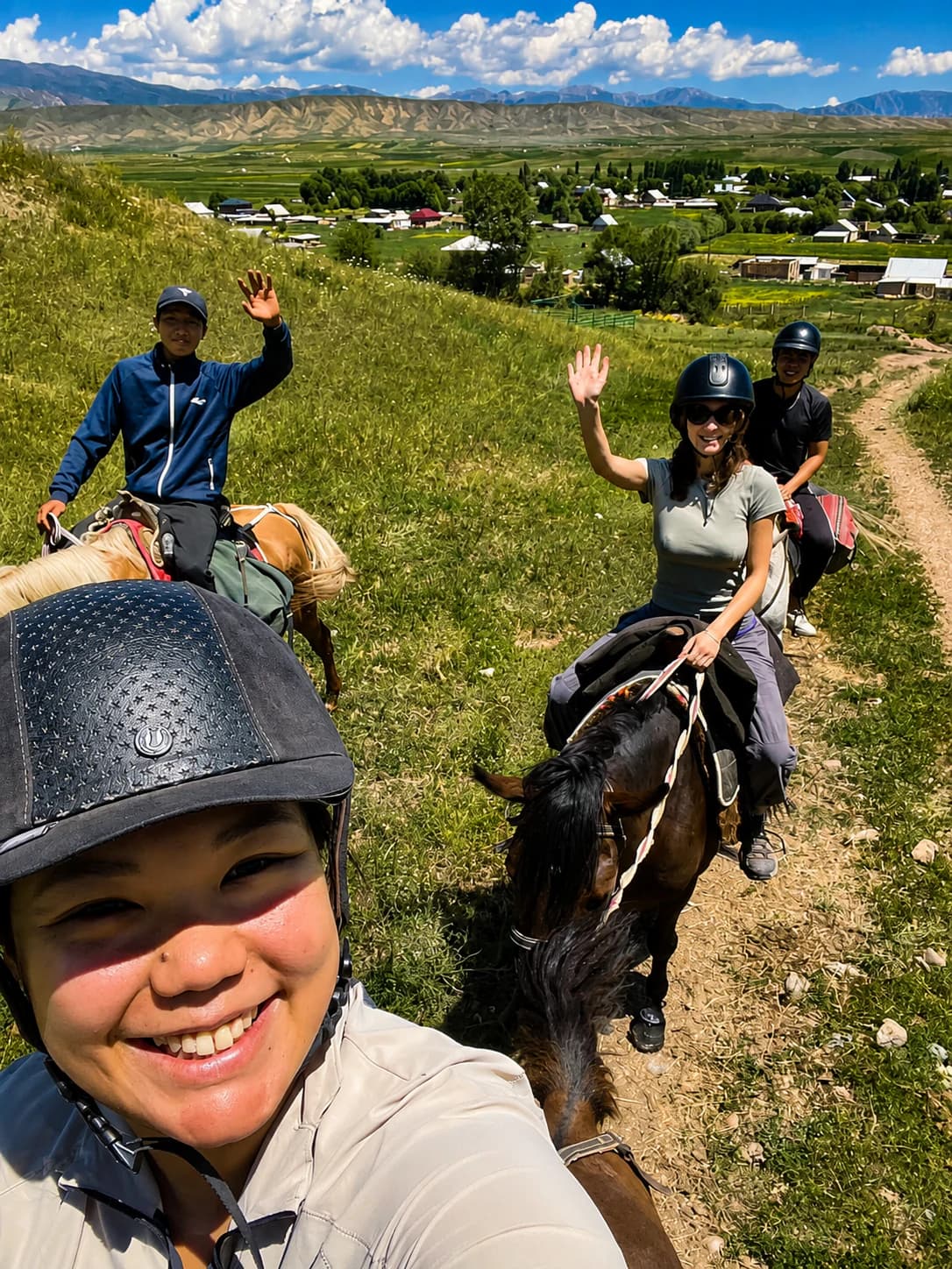 Horse riders crossing a sunny Kyrgyz hillside