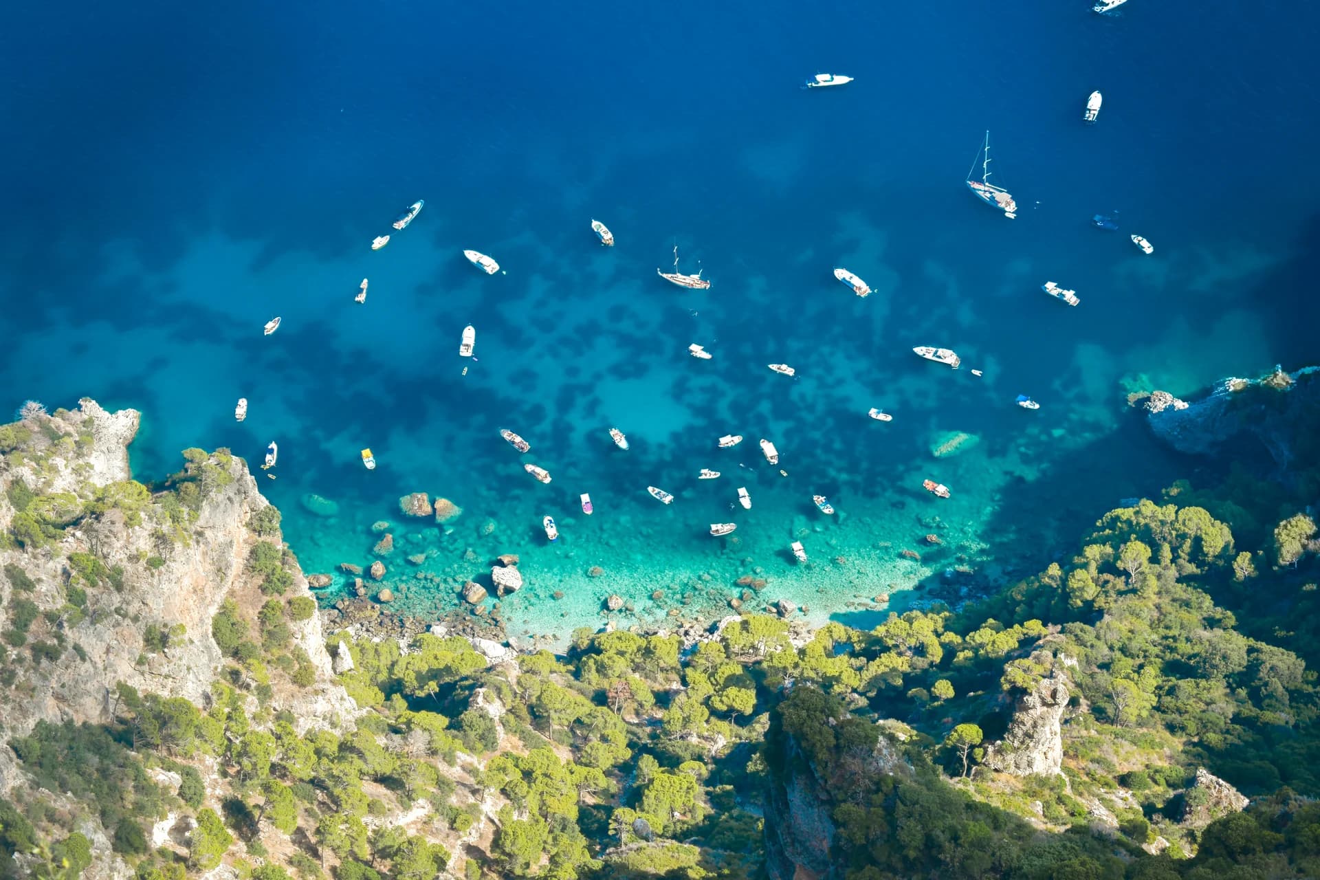 Boats floating in the clear blue water along Capri's rocky coast