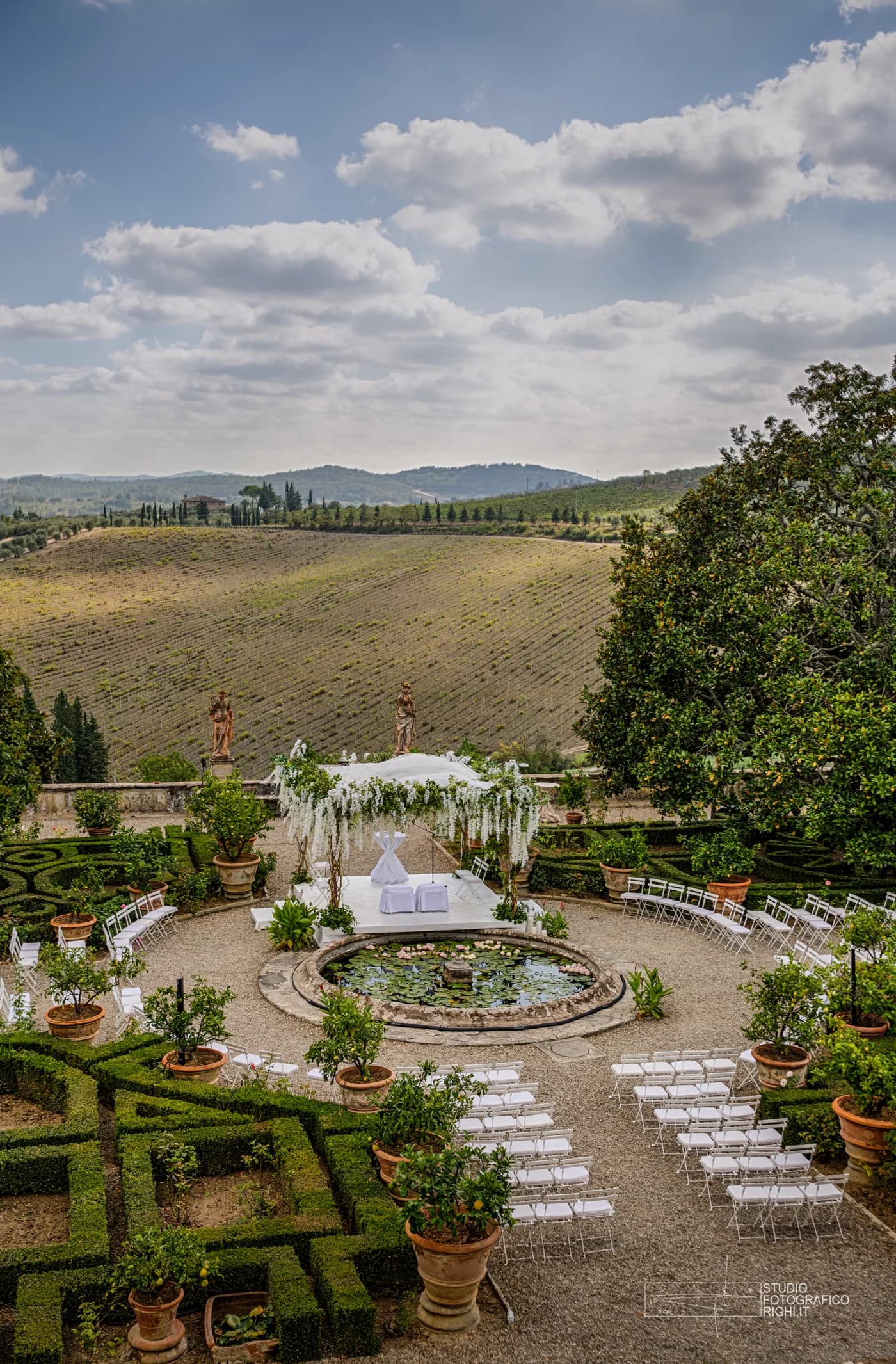 Garden wedding ceremony setup at a Tuscan villa overlooking vineyards