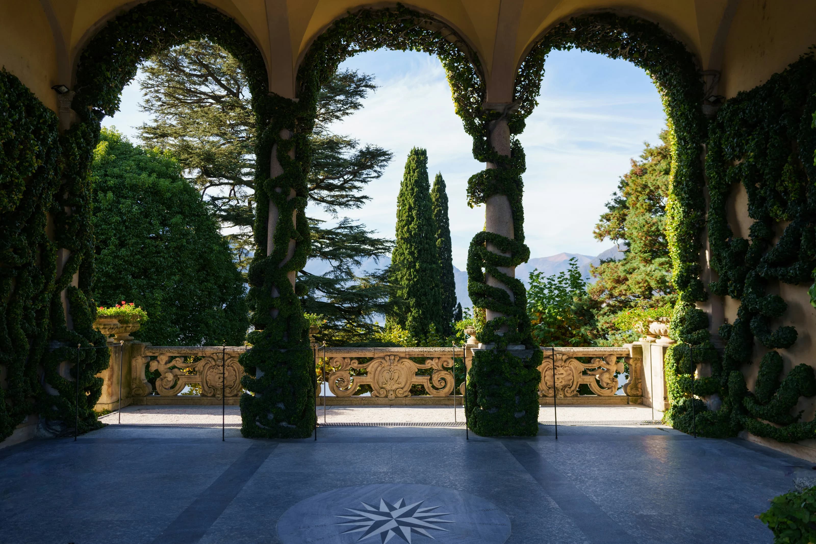 Ivy-covered arches framing an Italian garden and mountain landscape